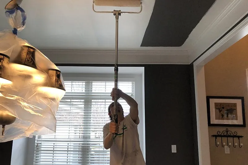 worker painting a ceiling in dining room