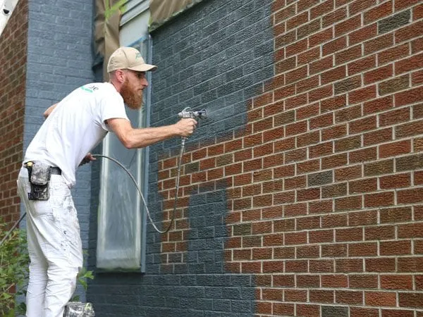 Spray painting a houses brick exterior in Scio Township