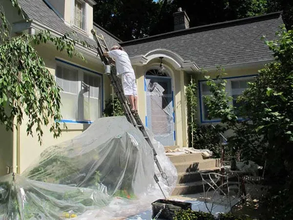 Man painting home exterior after prepping it