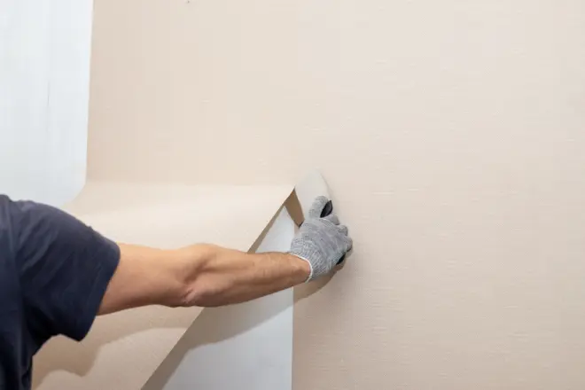 a person using a scraper to remove wallpaper. - wallpaper removal